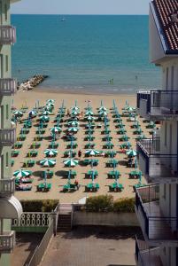a beach with chairs and umbrellas and the ocean at Appartamenti Emma in Caorle