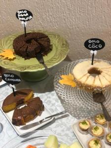 a table topped with cakes and desserts on plates at Hotel Pousada do Conde in Canela
