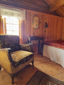 a bedroom with a bed and a chair and a mirror at Ålbyggården in Røros