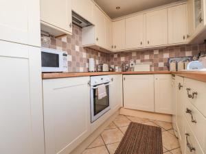 a kitchen with white cabinets and a microwave at Old Hollow Cottage in Southport