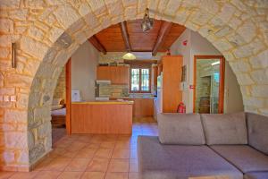sala de estar con sofá y pared de piedra en Villa Vrisses by PosarelliVillas en Vryses