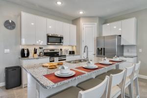 a kitchen with white cabinets and a large kitchen island with chairs at Formosa Valley by UNE Homes in Orlando