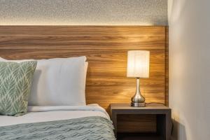 a bed with a wooden headboard and a lamp on a table at Formosa Valley by UNE Homes in Orlando