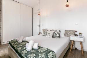 a white bedroom with a large bed with pillows at Casa Trilhos da Serra in Alcobertas