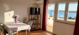 a dining room with a table with a vase of flowers at Apartments Donadic I, Caska in Novalja
