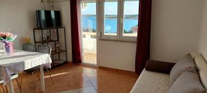 a living room with a table and a view of the ocean at Apartments Donadic I, Caska in Novalja