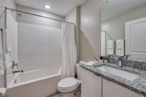 a white bathroom with a tub and a toilet and a sink at Formosa Valley by UNE Homes in Orlando