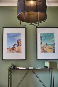 a chandelier and two pictures on a green wall at Demeure de Manneville - SPA - 1Km des plages de Cabourg in Dives-sur-Mer