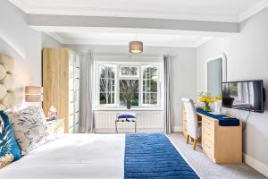 a bedroom with a bed and a desk and a tv at The Coast House B&B and Spa in Bognor Regis