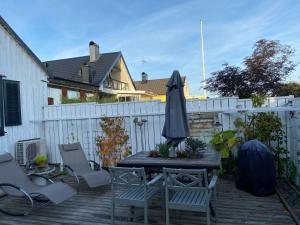 een patio met een tafel en stoelen en een parasol bij B&B Bland ormbunkar och rosor in Falkenberg