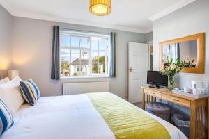 a bedroom with a bed and a television and a window at The Coast House B&B and Spa in Bognor Regis