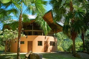 uma casa com palmeiras em frente em Manoas em Uvita