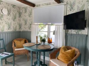 a living room with a table and chairs and a tv at B&B Bland ormbunkar och rosor in Falkenberg