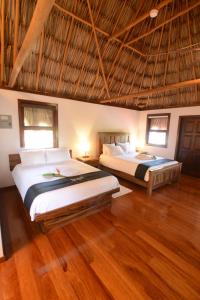 a bedroom with two beds and a straw roof at El Ben Cabañas in Caye Caulker
