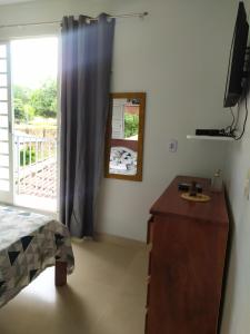 sypialnia z komodą i przesuwnymi szklanymi drzwiami w obiekcie Kitnet em Alter do Chão w mieście Alter do Chao