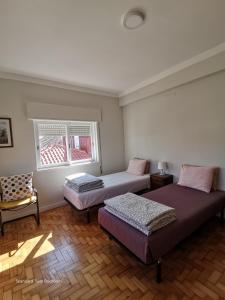 Cette chambre dispose de deux lits, d'une chaise et d'une fenêtre. dans l'établissement Alex Point - Guest House, à Viana do Castelo