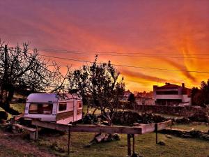 un wagon garé dans un champ avec un coucher de soleil dans l'établissement Albergue Casa do Sardão, à Carreço