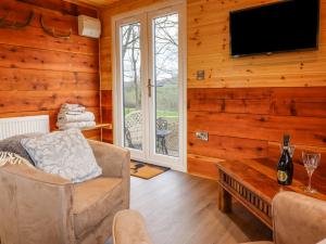 uma sala de estar com uma televisão, um sofá e uma mesa em Stag Lodge Pod em Welshpool