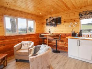 una cocina en una cabaña de madera con 2 sillas y una barra en Stag Lodge Pod, en Welshpool