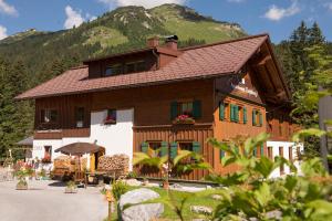 ein großes Holzhaus mit einem Berg im Hintergrund in der Unterkunft Appartement Omesberg 1 in Lech am Arlberg