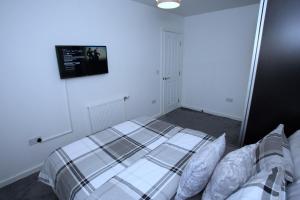 a bedroom with a bed and a tv on the wall at Amersham Park Apartment in Manchester