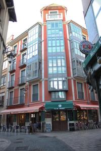 un edificio alto de color rojo con ventanas en una calle de la ciudad en Piso Molly, en León