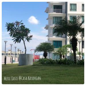 a tall white building with palm trees in front of it at Meru Oasis at Casa Kayangan Ipoh in Ipoh