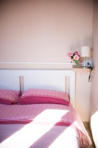 ein Bett mit rosa Kissen und einer Blumenvase in der Unterkunft Lory's Home in Caiazzo