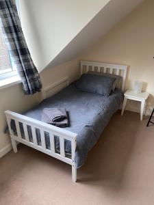 a white bed in a room with a window at Cosy 3-bedroom house, stones throw to beach in Weymouth