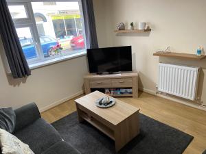 a living room with a couch and a tv and a table at Cosy 3-bedroom house, stones throw to beach in Weymouth