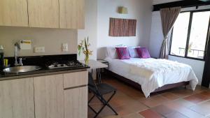 een slaapkamer met een bed met roze kussens en een wastafel bij Ecolodge Bahia del Peñón in Guatapé