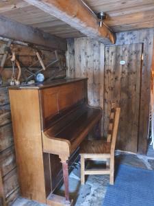 a wooden piano and a chair in a room at Ålbyggården in Røros