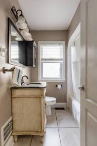 a bathroom with a sink and a toilet and a window at Pet Friendly - Large Families - Heart of Royal Oak - 5 Smart TVs in Royal Oak