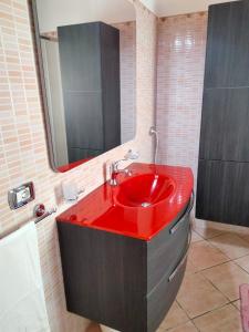 a bathroom with a red sink and a mirror at CASA VACANZA NEL GIARDINO DELLE VIGNE in Chiaramonte Gulfi