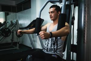 a man sitting on a gym machine lifting weights at Hotel Mirage in La Piedad Cavadas