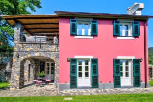 ein rosafarbenes Haus mit grünen Rollläden in der Unterkunft I Giardini di Camogli - VILLA SÀRVIA, garden&pool in Camogli
