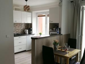 a kitchen with white cabinets and a wooden table at Draugystės Apartment in Šiauliai