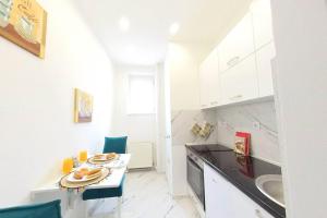a small white kitchen with a table and a sink at Cute and Sunny Studio - Central Location in Sarajevo