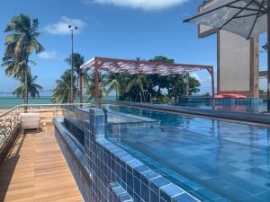 uma piscina com vista para o oceano em Netuanah Praia Hotel em João Pessoa