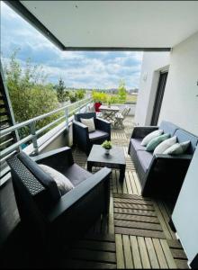 eine Terrasse mit Sofas und Tischen auf dem Balkon in der Unterkunft Joli appartement Proche Disney in Chanteloup-en-Brie