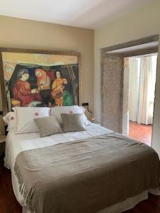 a bedroom with a large bed with a painting on the wall at CASA DO ARXENTINO in Mera