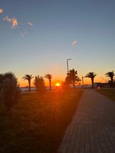 a sunset in a field with palm trees and a sidewalk at Luxury Apartment Sea View Soho City 5th floor in Bar