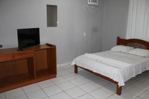 a bedroom with a bed and a flat screen tv at Artidoros Hotel in Pedro Gomes +18 photos