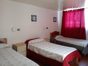 Un dormitorio con dos camas y una cortina roja. en Residencial la Cabaña, en Santiago