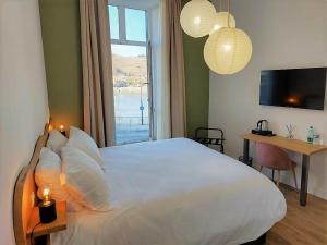 a bedroom with a large white bed with a window at Le Château in Tournon-sur-Rhône