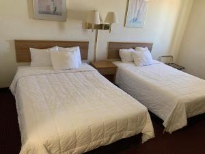 duas camas num quarto de hotel com lençóis brancos em Plaza Inn Lordsburg I-10 em Lordsburg
