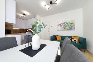 una sala de estar con una mesa blanca con un jarrón de flores en Apartment Alegria Zadar, en Zadar