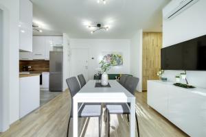 Una cocina y un comedor con una mesa y sillas blancas. en Apartment Alegria Zadar, en Zadar
