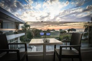 un balcone con tavolo, sedie e ampia finestra di Seaside Luxury Apartments Kremasti a Kremasti