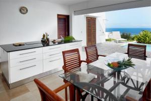 a kitchen and dining room with a glass table and chairs at Savane Paille in Deshaies
